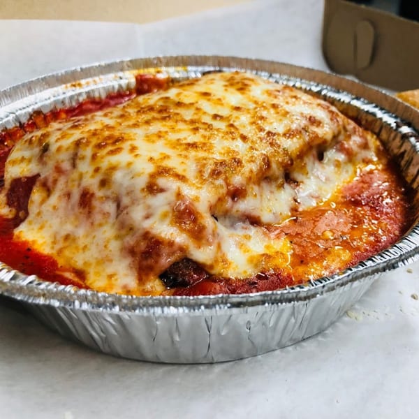 Baked lasagna with melted cheese and red sauce in a silver foil container.
