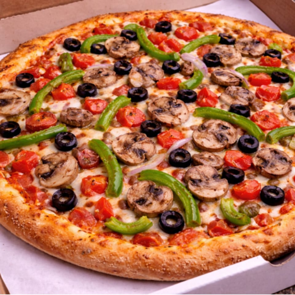 A whole pizza with mushrooms, green peppers, black olives, and diced tomatoes in a box.