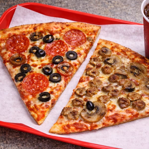 Two pizza slices, one with pepperoni and olives, the other with sausage and mushrooms, on a red tray.